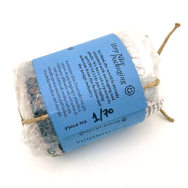Back view of the Ceramic Pot Candle packaging, featuring a label explaining the upcycled materials sourced from the fashion and design industry, secured with natural cord.