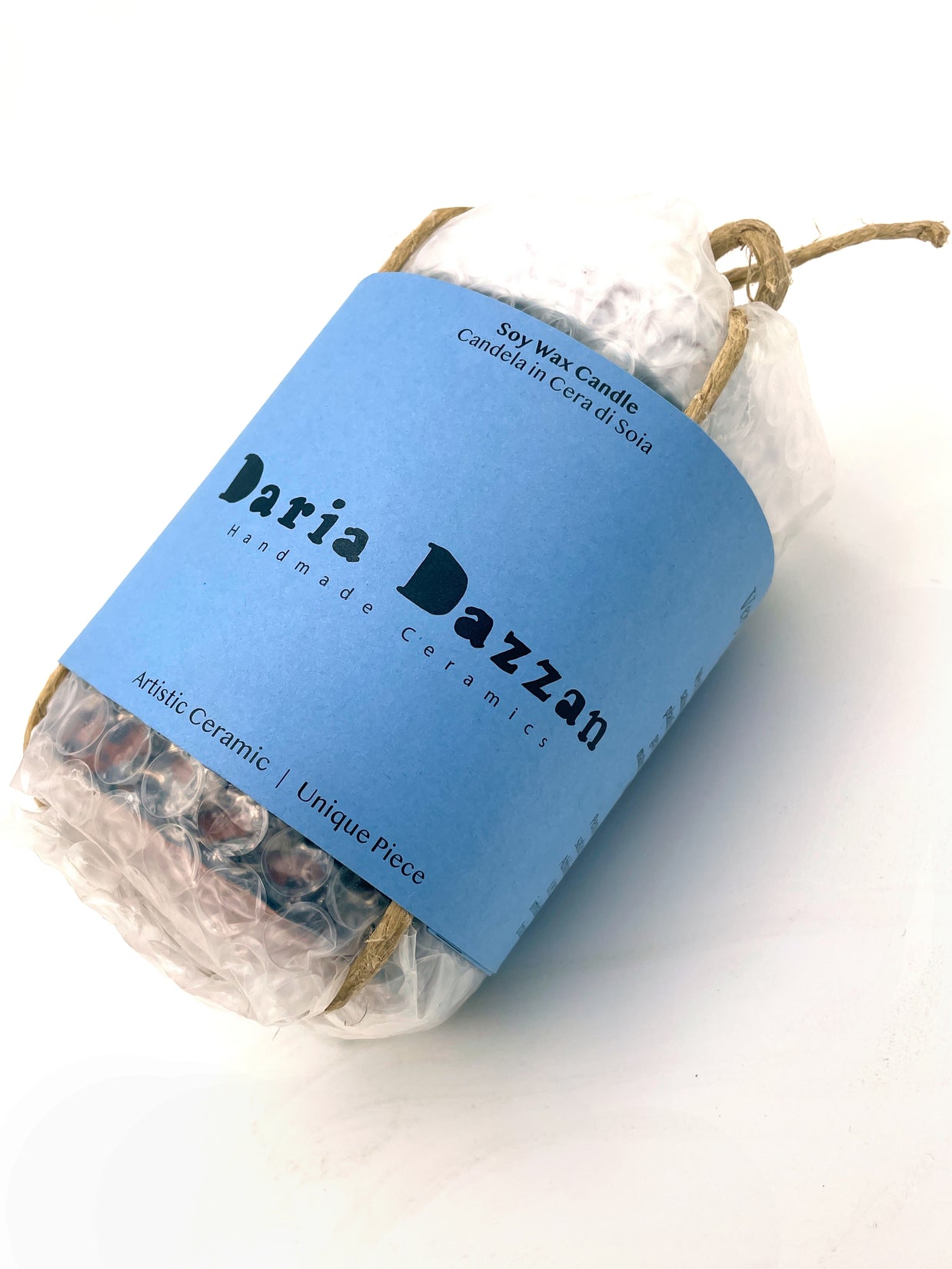 Ceramic Pot Candle wrapped in bubble wrap, secured with a natural cord and branded label showcasing the Daria Dazzan logo.