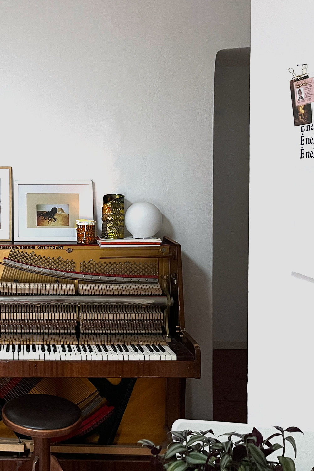 Detail of a white-walled room with a piano, featuring Ceramic Pot Candles in platinum glaze elegantly placed on top, adding a touch of artisanal sophistication to the decor.