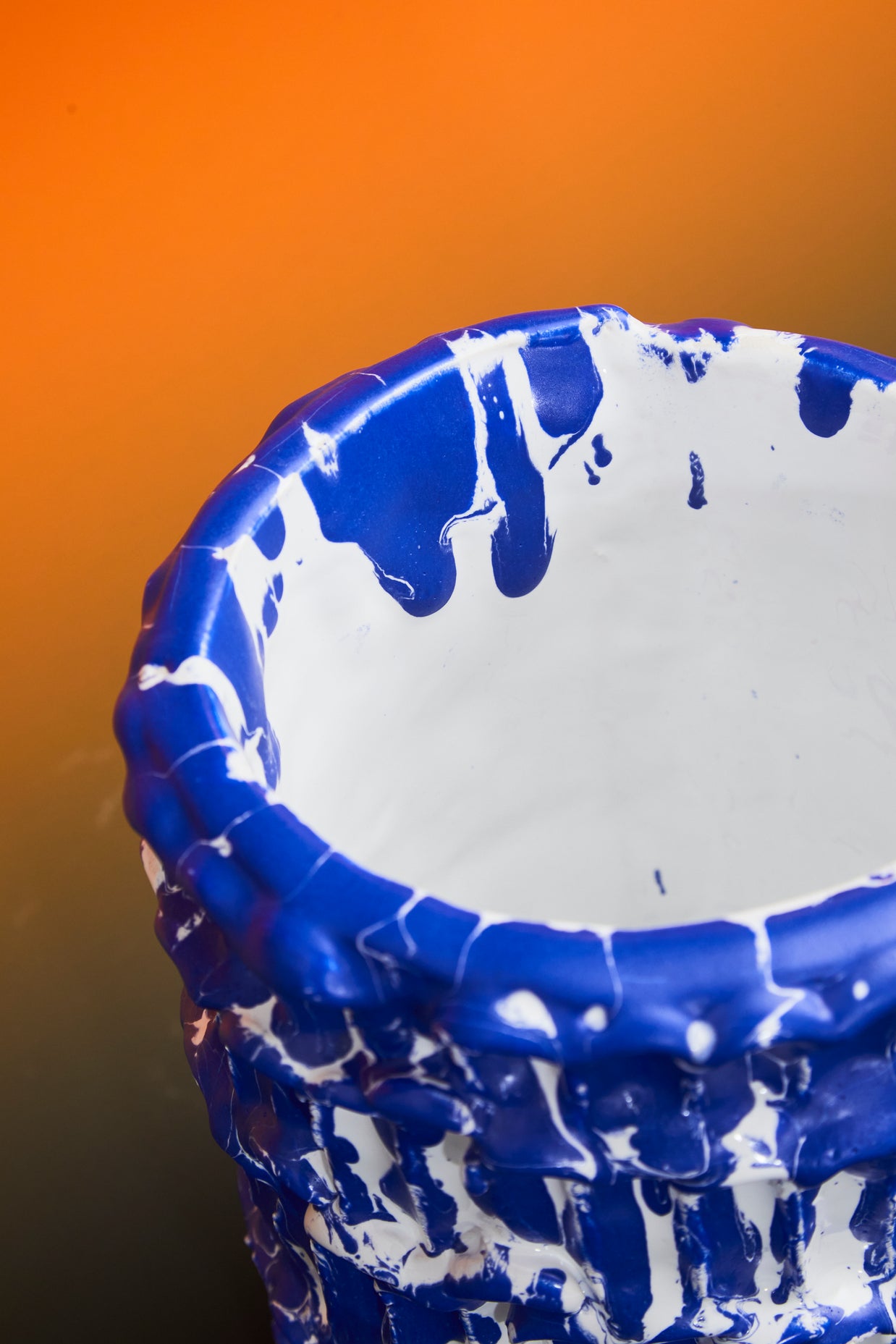 Upper side view of the Ceramic Vase in Egyptian Blue and White, displayed on an orange background, accentuating its smooth lines and glossy finish.