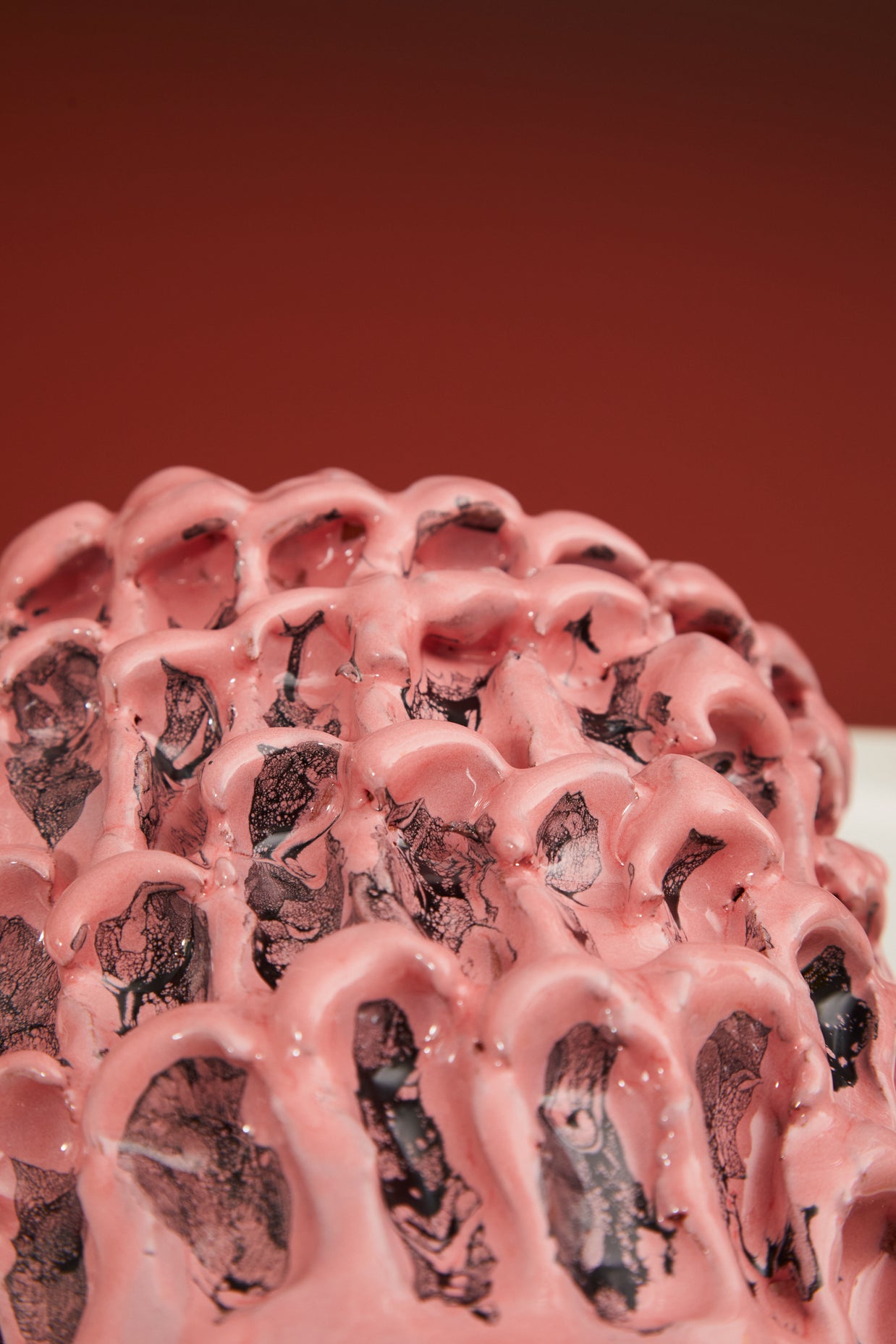 Close-up detail of the Ceramic Vase in Haime Pink and Liquorice, set against a brick-colored background, highlighting its texture and color gradation.