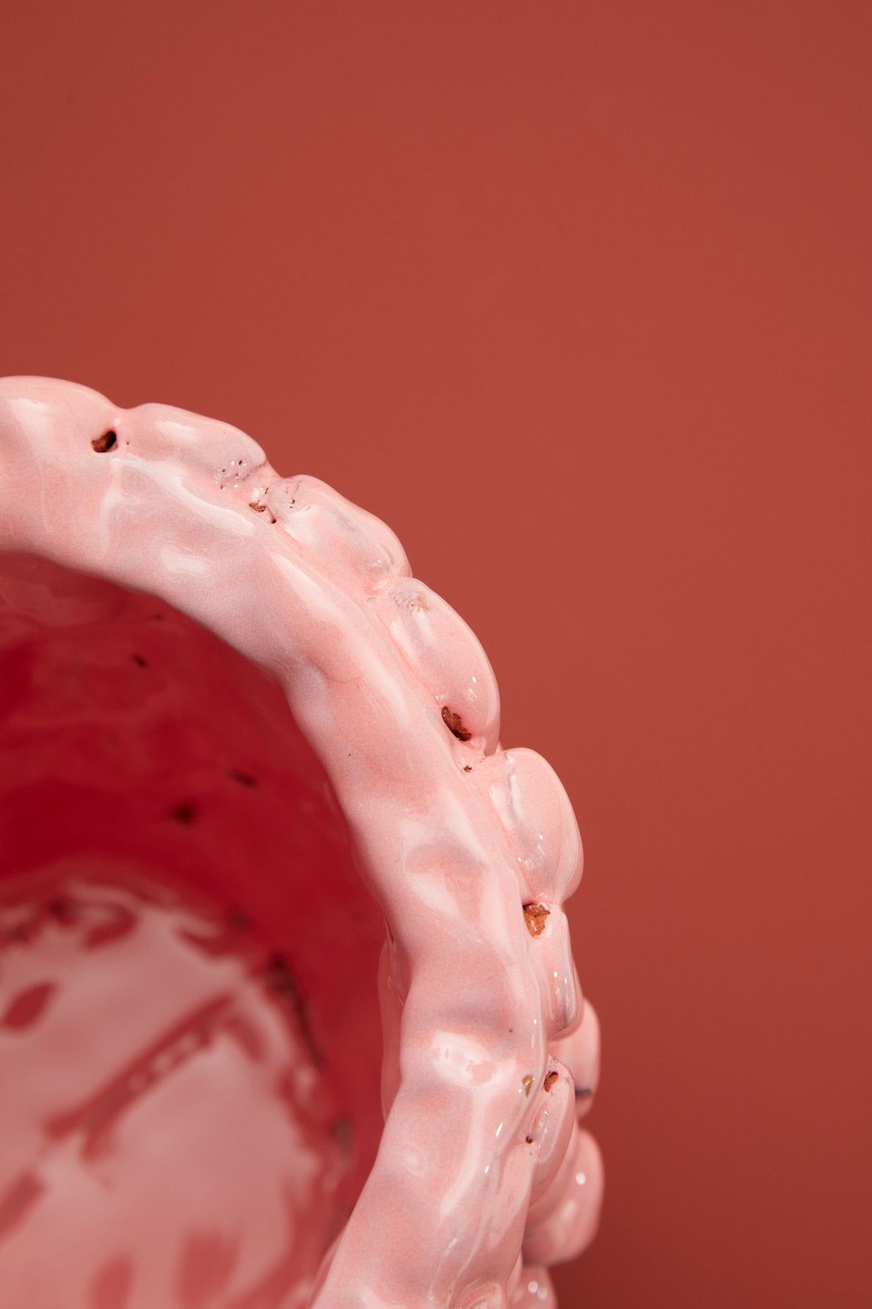 Upper rim view of the Ceramic Vase in Haime Pink and Liquorice, displayed against a brick-colored background, accentuating the delicate wave-like edge and uniform pink colour.