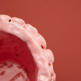 Upper rim view of the Ceramic Vase in Haime Pink and Liquorice, displayed against a brick-colored background, accentuating the delicate wave-like edge and uniform pink colour.