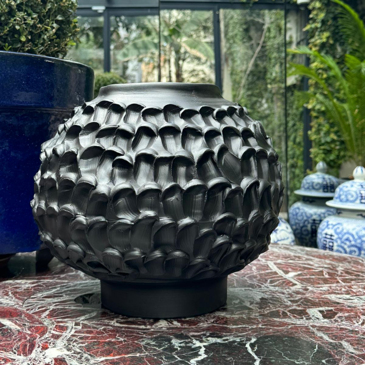 Close-up of the Ceramic Vase in Licorice Black as part of the indoor marble table composition, showcasing its refined design against the complementary blue elements.