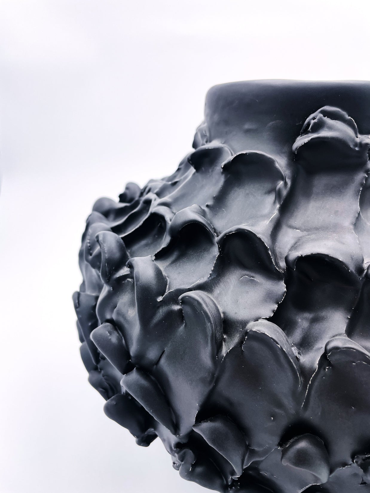 Side detail of the Ceramic Vase in Licorice Black, highlighting the smooth curves and elegant form of the vase, with its black finish against a white backdrop.