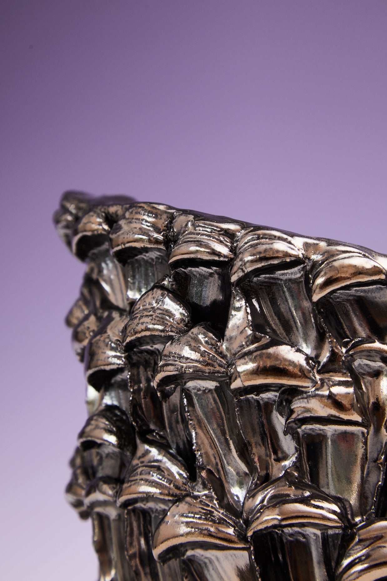Close-up of the side border of the Ceramic Vase in Metallic Platinum, highlighting its reflective edge against a gradient background from white to violet.