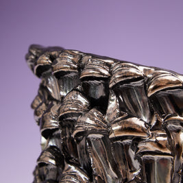 Close-up of the side border of the Ceramic Vase in Metallic Platinum, highlighting its reflective edge against a gradient background from white to violet.