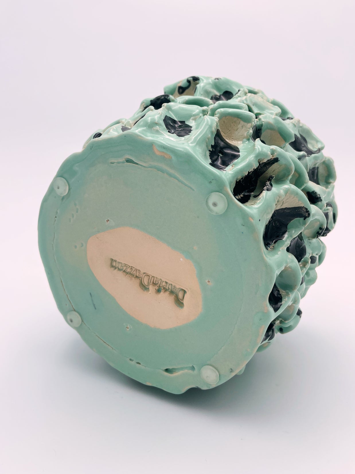 Bottom view of the Ceramic Vase in Tiffany and Pitch Black, showcasing the artist's signature on the base, set against a light pink background.