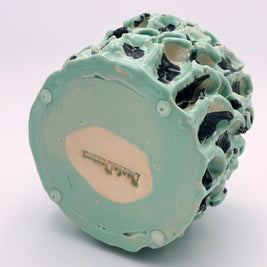 Bottom view of the Ceramic Vase in Tiffany and Pitch Black, showcasing the artist's signature on the base, set against a light pink background.