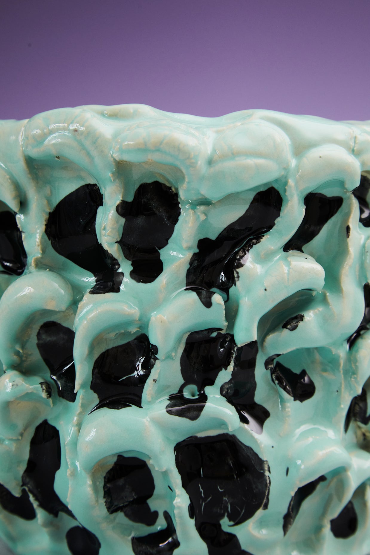 Close-up view of the upper edge of the Ceramic Vase in Tiffany and Pitch Black, showcasing the smooth contours and black wave insert details, set against a purple background.