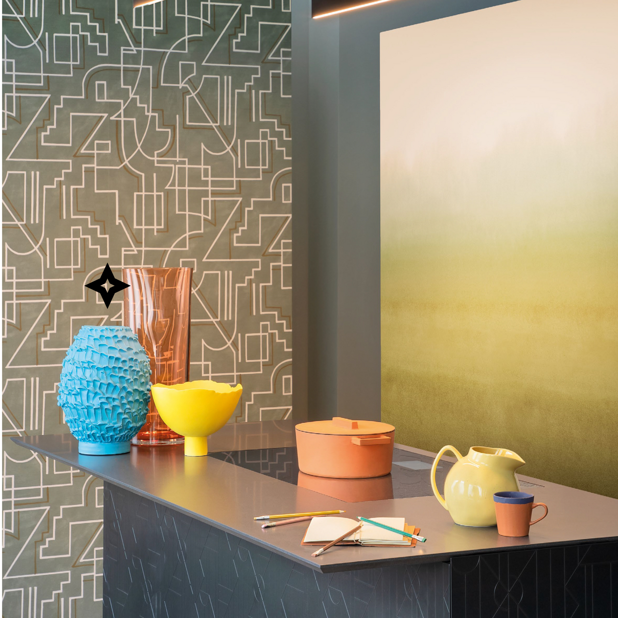 Modern arrangement with the Ceramic Vase in Whispy Blue on a sleek grey-black countertop, surrounded by two smooth vases, a notebook, pen set, teapot, cup, and pot, with a futuristic patterned background showing a yellow wall art.